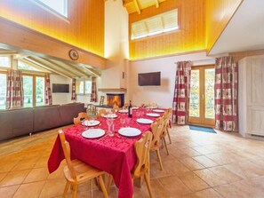 A dining area with a long table set for a meal, wooden chairs, a fireplace, and large windows. - Chalet Pierina by Interhome (La Tzoumaz)