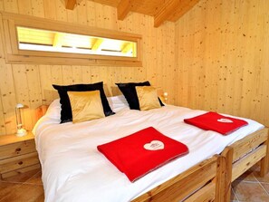 A wooden-paneled room with a bed, a nightstand, a lamp, and a skylight. - Chalet Pierina by Interhome (La Tzoumaz)