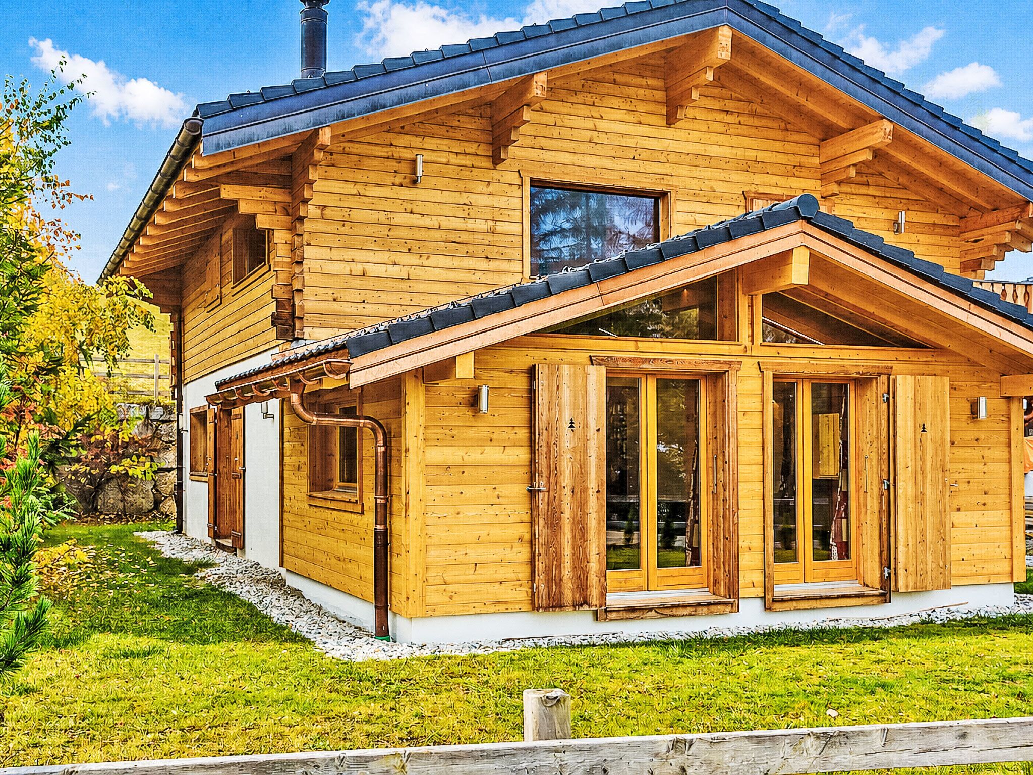 Une maison en bois avec un toit en pente, de grandes fenêtres et une véranda couverte.