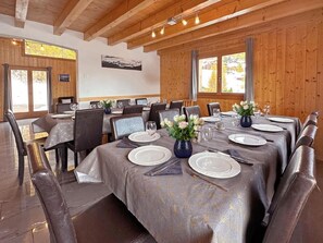 Ein Esszimmer mit Holzwänden, großen Fenstern und einem Tisch für sechs Personen.