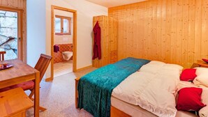 A wooden-paneled room with a bed, a table, and a chair. - Chalet Julia by Interhome (La Tzoumaz)