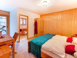 A wooden-paneled room with a bed, a table, and a chair. - Chalet Julia by Interhome (La Tzoumaz)