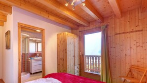 A wooden cabin bedroom with a bed, a bathroom, and a balcony. - Chalet Julia by Interhome (La Tzoumaz)
