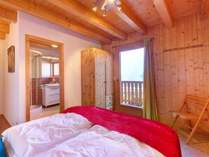 A wooden cabin bedroom with a bed, a bathroom, and a balcony. - Chalet Julia by Interhome (La Tzoumaz)