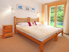 Ein Schlafzimmer mit einem hölzernen Bett, einem Nachttisch, einer Kommode und einem Fenster mit Vorhängen.