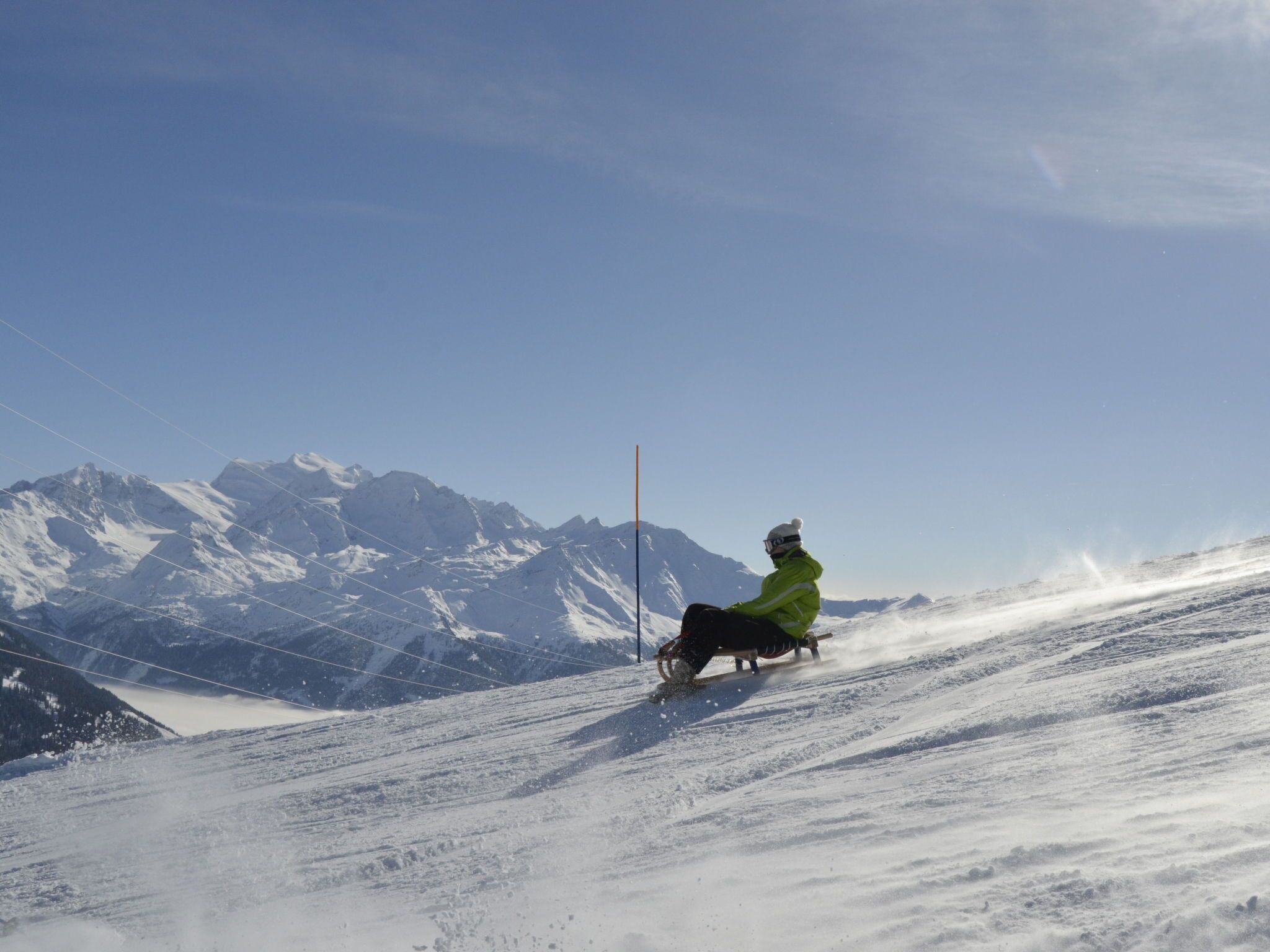 A person skiing down a snowy slope with mountains in the background.