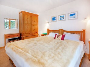A bedroom with a large bed, wooden wardrobe, bedside tables, and framed pictures on the wall. - Chalet Charmille by Interhome (La Tzoumaz)