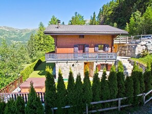 Ein Chalet mit Balkon, Stein Fundament und Blick auf die umliegenden Berge.