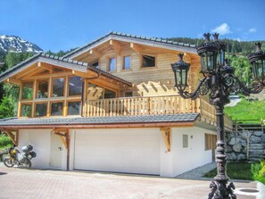 Eine Holzchalet mit großen Fenstern, einem Balkon und einer Garage.