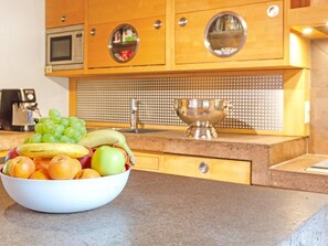 Eine Küche mit Holzschränken, einer Mikrowelle, einem Spülbecken und einer Obstschüssel auf der Arbeitsplatte.