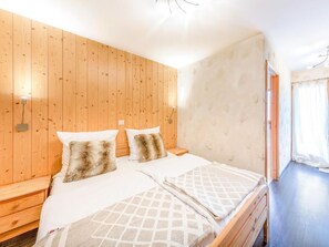 Ein Zimmer mit einem hölzernen Kopfteil, einem Bett mit zwei Kissen, einem Nachttisch und einer Wandleuchte.