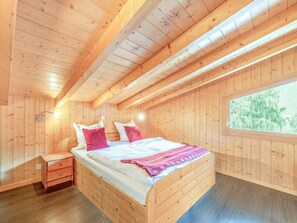 Ein Schlafzimmer einer Holzhütte mit einem Bett, Nachttischen und einem Fenster.