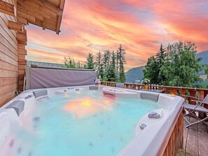 Ein Whirlpool auf einer Holzterrasse mit Blick auf Bäume und Berge.