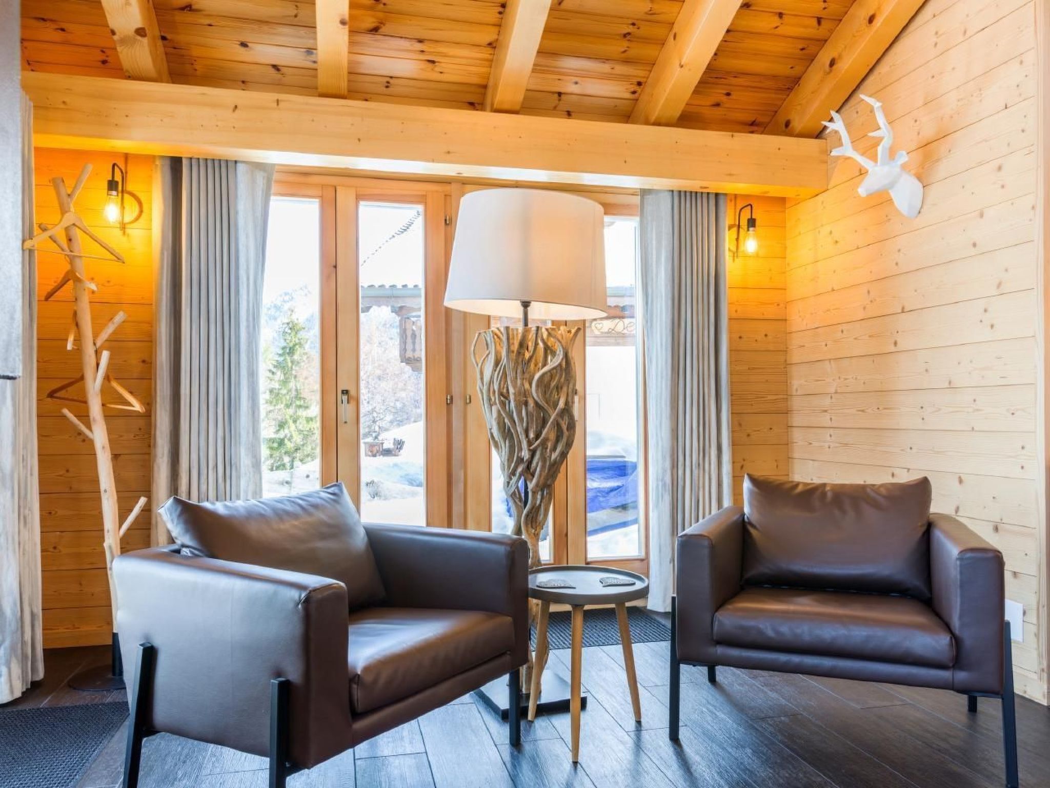 Une pièce avec deux canapés en cuir, un lampadaire et un plafond en bois.