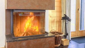Ein Kamin mit Feuer, eine Holzwand und eine Tür.