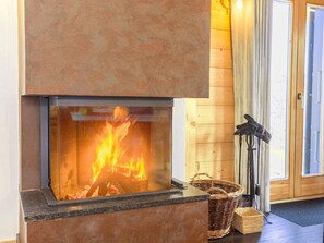 Ein Kamin mit Feuer, eine Holzwand und eine Tür.