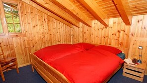 A wooden room with a bed, a chair, and a window. - Chalet Alpina by Interhome (La Tzoumaz)