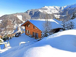 A wooden cabin with a snow-covered roof, surrounded by mountains and snow. - Chalet Alpina by Interhome (La Tzoumaz)