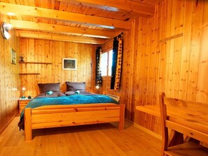 A wooden cabin bedroom with a bed, a chair, and a nightstand. - Chalet Alpina by Interhome (La Tzoumaz)
