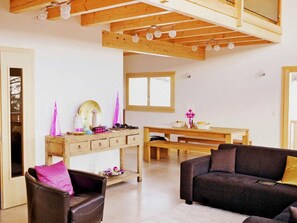 A spacious living area with a high ceiling, wooden beams, a dining table, and a sofa. - Chalet Chaud by Interhome (La Tzoumaz)