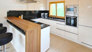 A modern kitchen with white cabinets, a wooden island, a built-in oven, and a window. - Chalet Chaud by Interhome (La Tzoumaz)