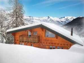 Eine Holzhütte mit einem Balkon, umgeben von schneebedeckten Bergen.