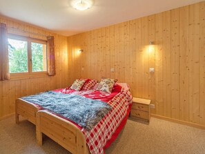 Ein Zimmer mit Holzwänden, einem Bett, einem Nachttisch und zwei Wandleuchten.