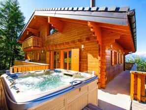 Une cabane en bois avec un jacuzzi et un balcon.
