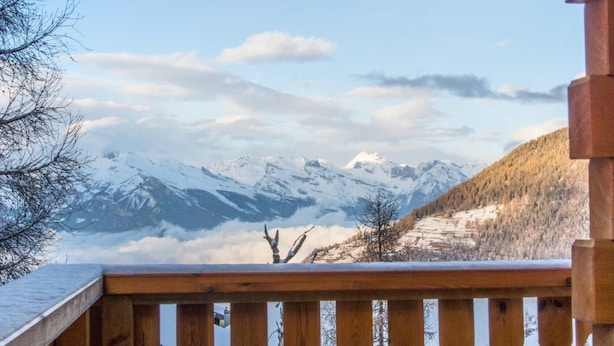 A wooden balcony overlooking a mountainous landscape with snow-covered peaks and a clear sky. - Chalet Harmonie by Interhome (La Tzoumaz)
