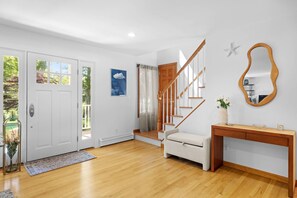 A modern interior with a wooden staircase, a white door, and a console table with a vase.