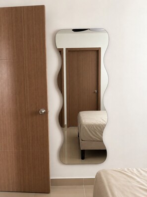 A bedroom with a wooden wardrobe, a bed, and a wall-mounted mirror. - Your  Peaceful tropical  Punta Cana Getaway 2BR Condo with all amenities & more (Punta Cana)