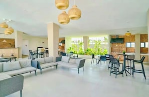 Amplio espacio interior con arreglos de asientos, incluyendo sofás y mesas, y una cocina al fondo.