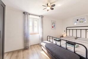 A bedroom with a bed, a ceiling fan, a window with curtains, and a wall-mounted artwork. - Summer Breeze Dominique 2BR Island Retreat, Veli Iž, Croatia (Veli Iž)