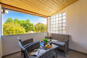 A balcony with wicker furniture, a table with a bottle and glasses, and a magazine. - Summer Breeze Dominique 2BR Island Retreat, Veli Iž, Croatia (Veli Iž)