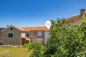 A stone building with a tiled roof, a door, and a window with shutters. - Summer Breeze Dominique 2BR Island Retreat, Veli Iž, Croatia (Veli Iž)