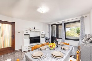 Un coin repas avec une table dressée pour quatre personnes, un téléviseur et un canapé avec des coussins.