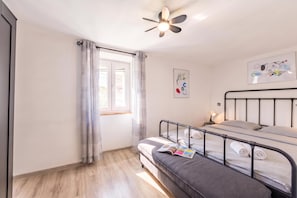 A bedroom with a bunk bed, a ceiling fan, a window with curtains, and a wall-mounted artwork. - Summer Breeze Dominique 2BR Island Retreat, Veli Iž, Croatia (Veli Iž)