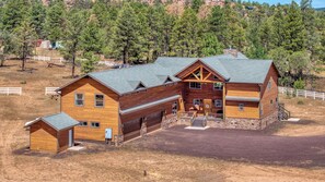 Eine große Holzhütte mit mehreren Zimmern und einer Garage, umgeben von einem eingezäunten Grundstück und Bäumen.