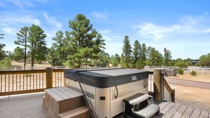 A hot tub on a wooden deck with a view of a fenced area and trees. - Fern Way Lodge-luxury-private pickleball/basketball court, hot tub, EV charger (Show Low)
