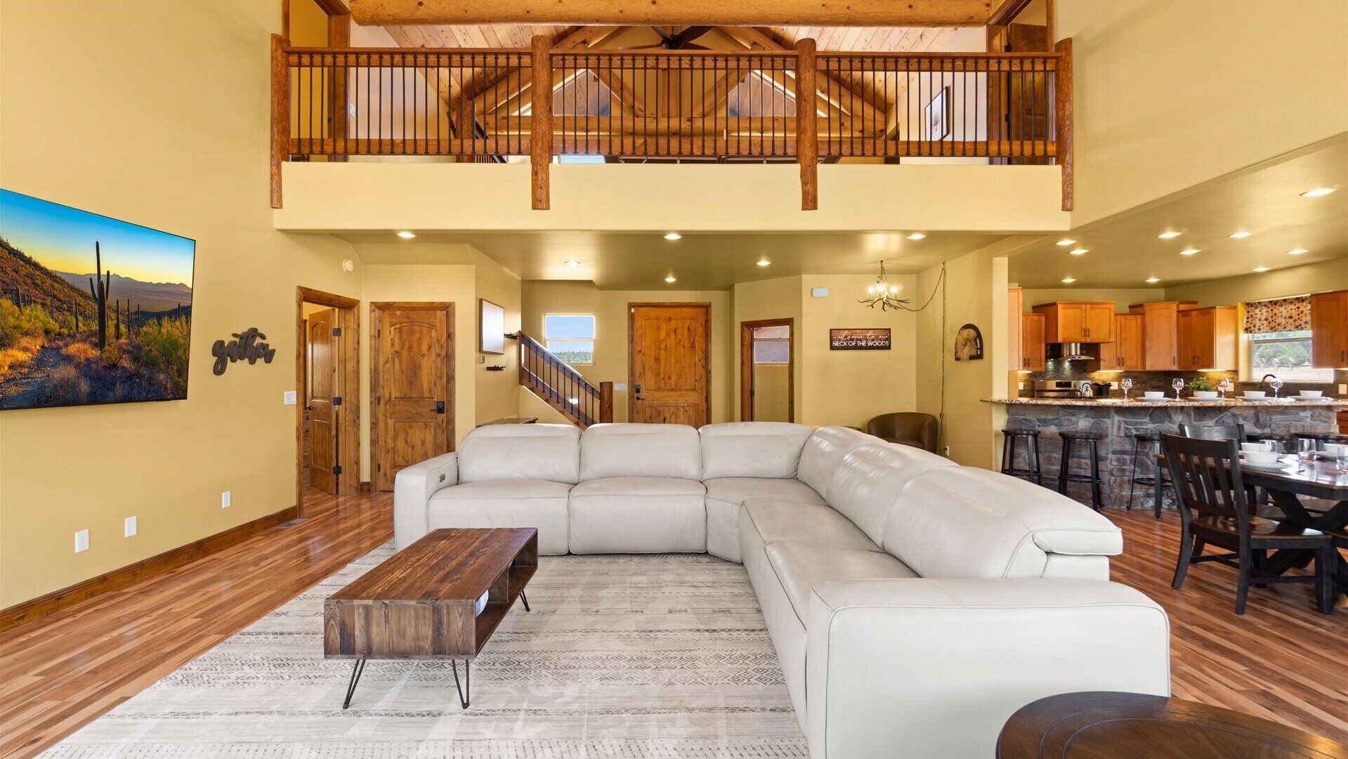 A spacious living area with a large sectional sofa, a wooden coffee table, and a kitchen in the background.