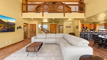 A spacious living area with a large sectional sofa, a wooden coffee table, and a kitchen in the background.
