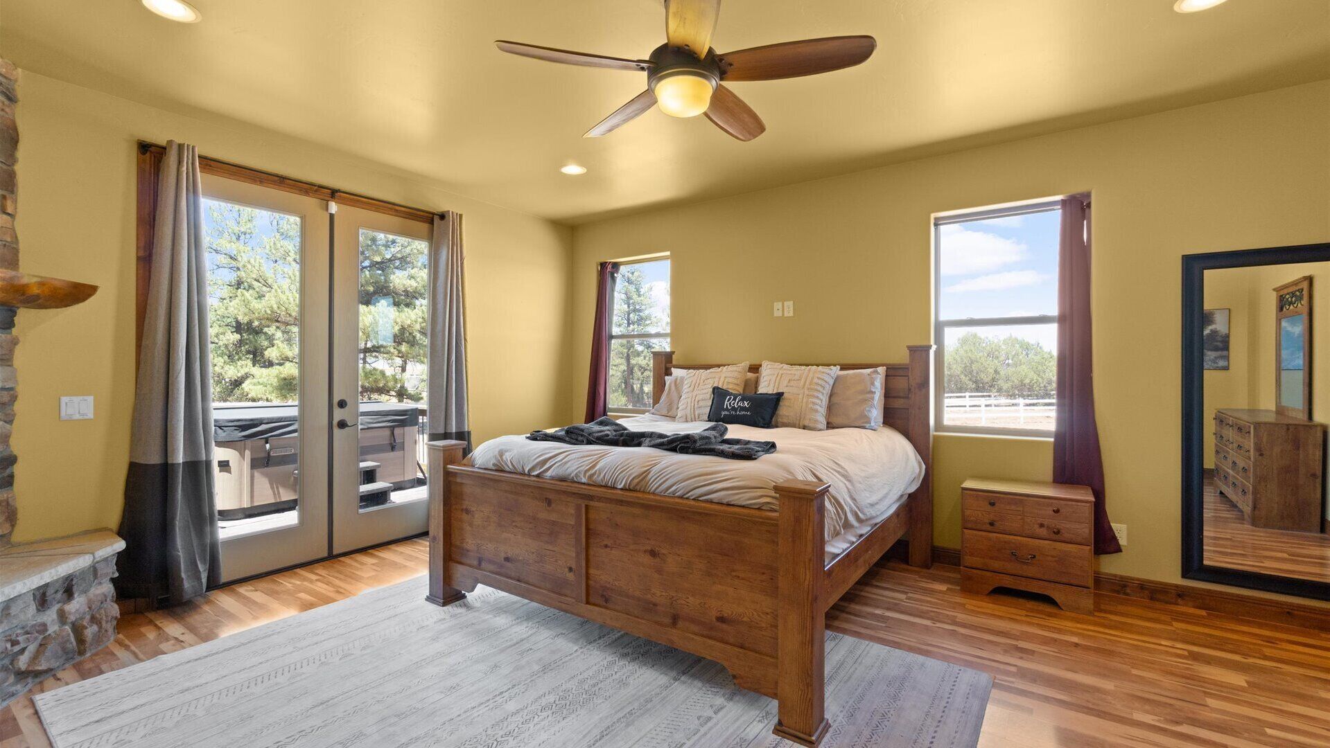 A bedroom with a wooden bed, a ceiling fan, and a view of the outdoors.