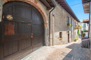A narrow cobblestone street with a large wooden door and a sign that reads 'ATTENZIONE AL CANE'. - The Place to Be, Outdoor dining, Laveno Mombello, Italy (Laveno Mombello)