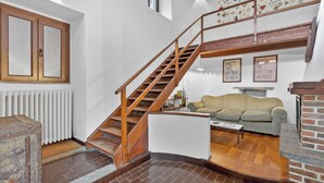 Un escalier avec des rampes en bois, un radiateur, un canapé et une cheminée.