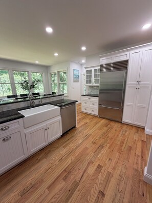 Una cocina moderna con muebles blancos, un refrigerador de acero inoxidable y piso de madera.