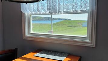 A dining area with a table, chairs, a lamp, and a window with a view of a landscape.