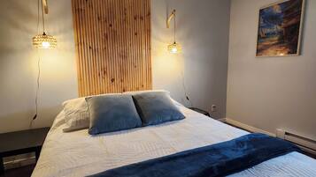 Une chambre à coucher avec un grand lit, deux lampes fixées au mur, un mur recouvert de panneaux en bois et un tableau.
