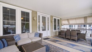A covered patio with wicker furniture, a cushioned sofa, and a patterned rug. - Luxury 6BR 3 BA Beach Home Sleeps 14 Huge Front Porch Walk To Beach and Downtown (Ocean City)