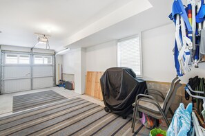 A garage with a large door, a workbench, and various tools and equipment. - Luxury 6BR 3 BA Beach Home Sleeps 14 Huge Front Porch Walk To Beach and Downtown (Ocean City)