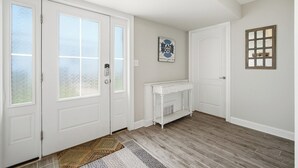 A room with a white door, a white fireplace, a rug, and a wall sign. - Luxury 6BR 3 BA Beach Home Sleeps 14 Huge Front Porch Walk To Beach and Downtown (Ocean City)
